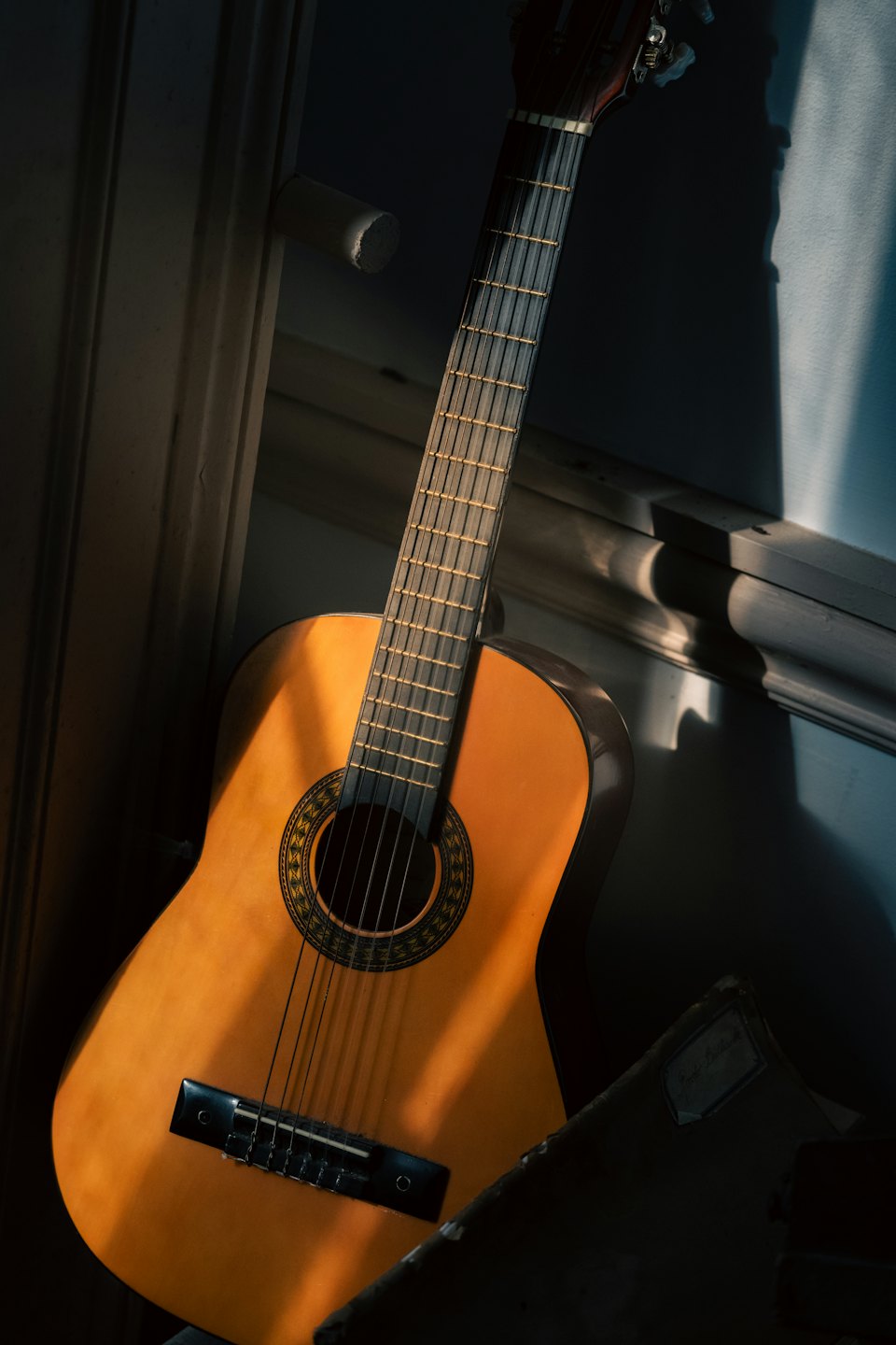 Een akoestische gitaar leunt tegen een muur naast een oud notitieboekje.