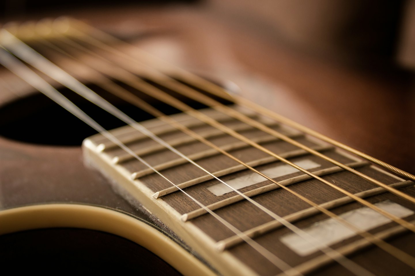 Metalen snaren op de houten toets van een akoestische gitaar.
